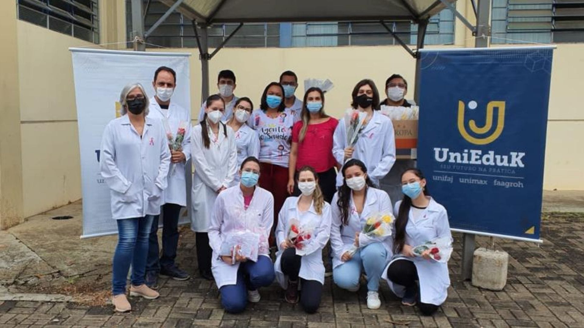 A imagem mostra os alunos da área de saúde durante as ações de conscientização sobre o câncer de mama e colo de útero.
