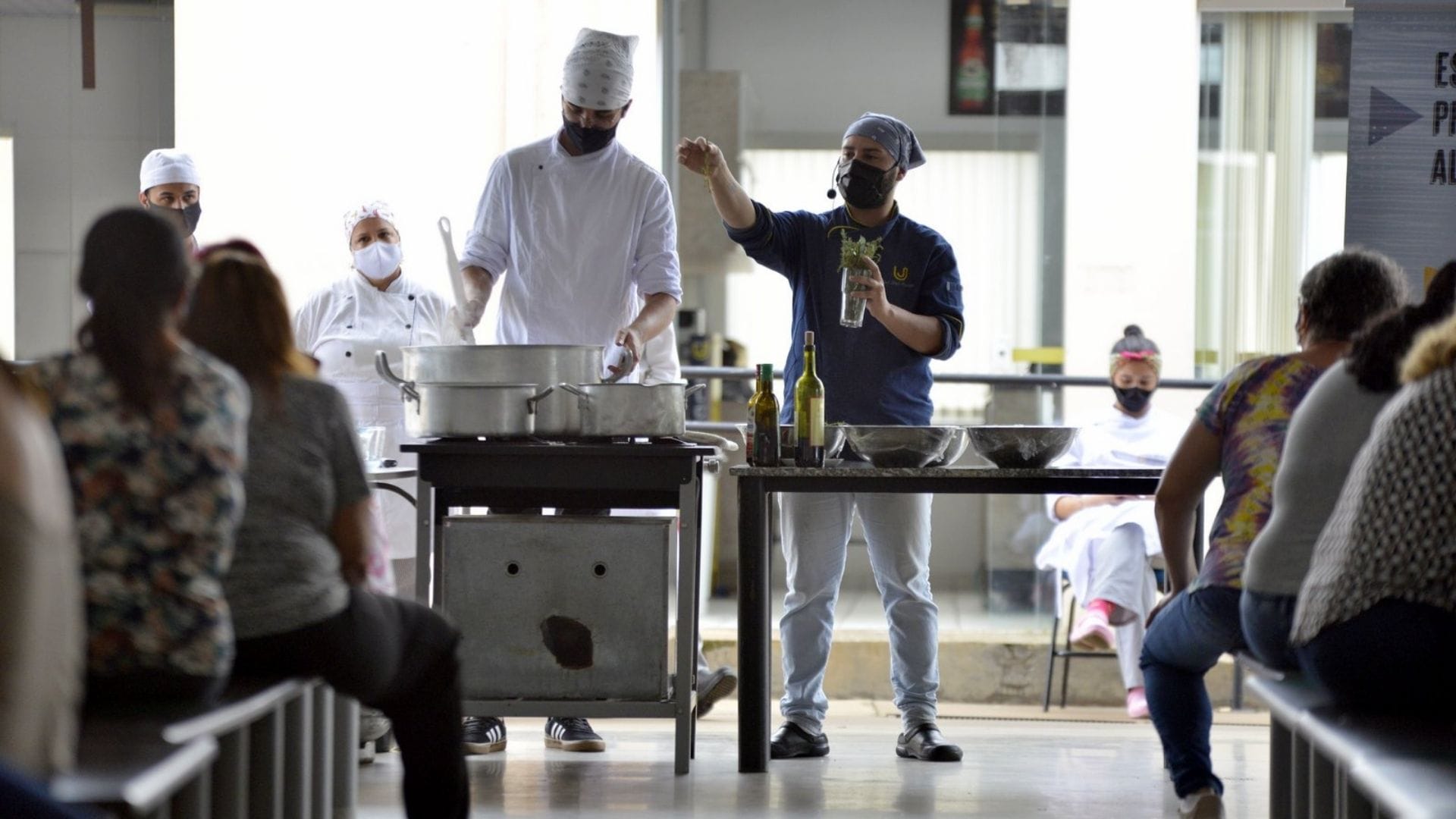 A imagem mostra os alunos preparando os alimentos e explicando os processos aos presentes durante o Tacho Solidário.