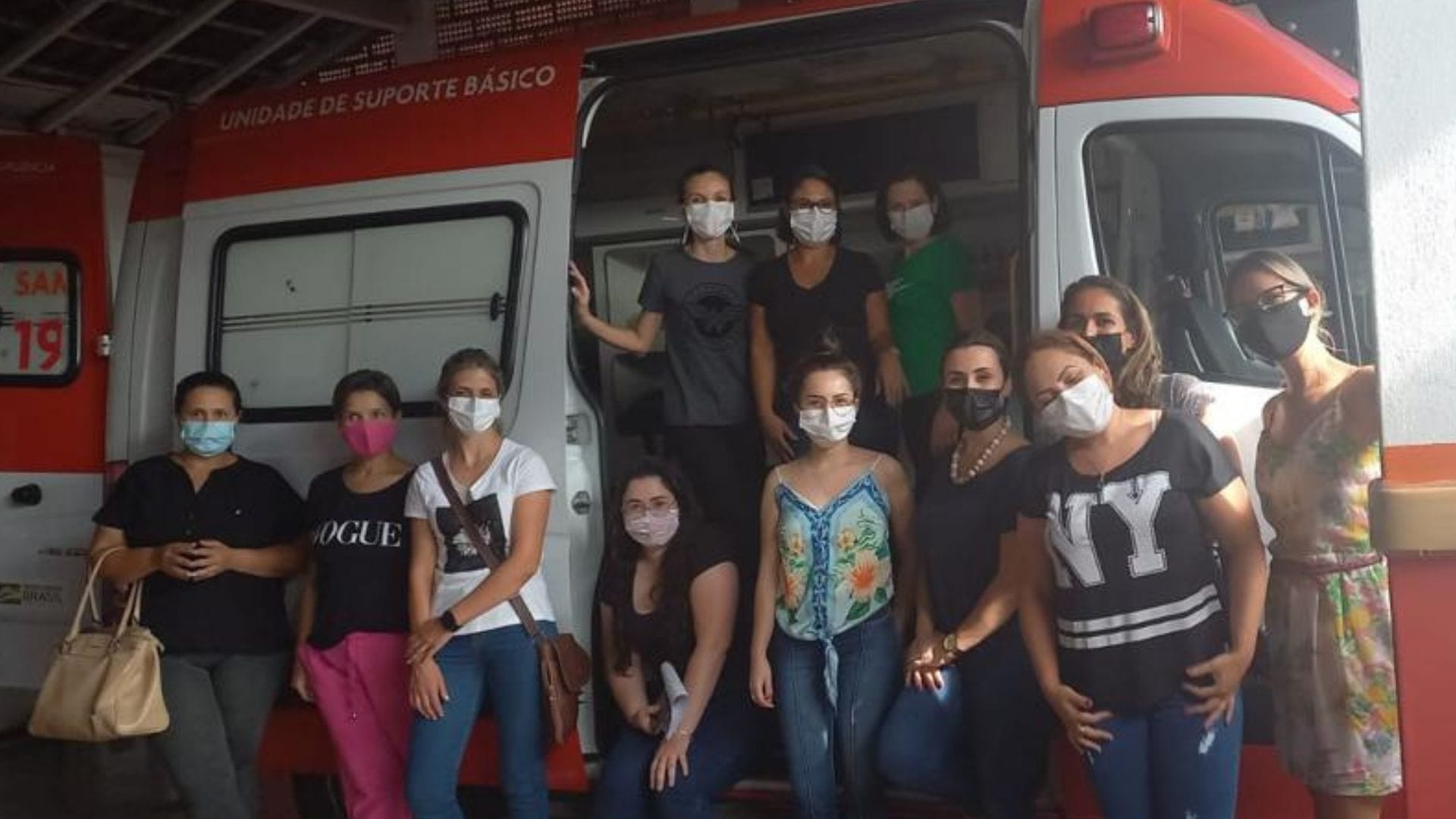 A imagem mostra alunas de pós graduação perto de uma ambulância durante a visita ao SAMU.
