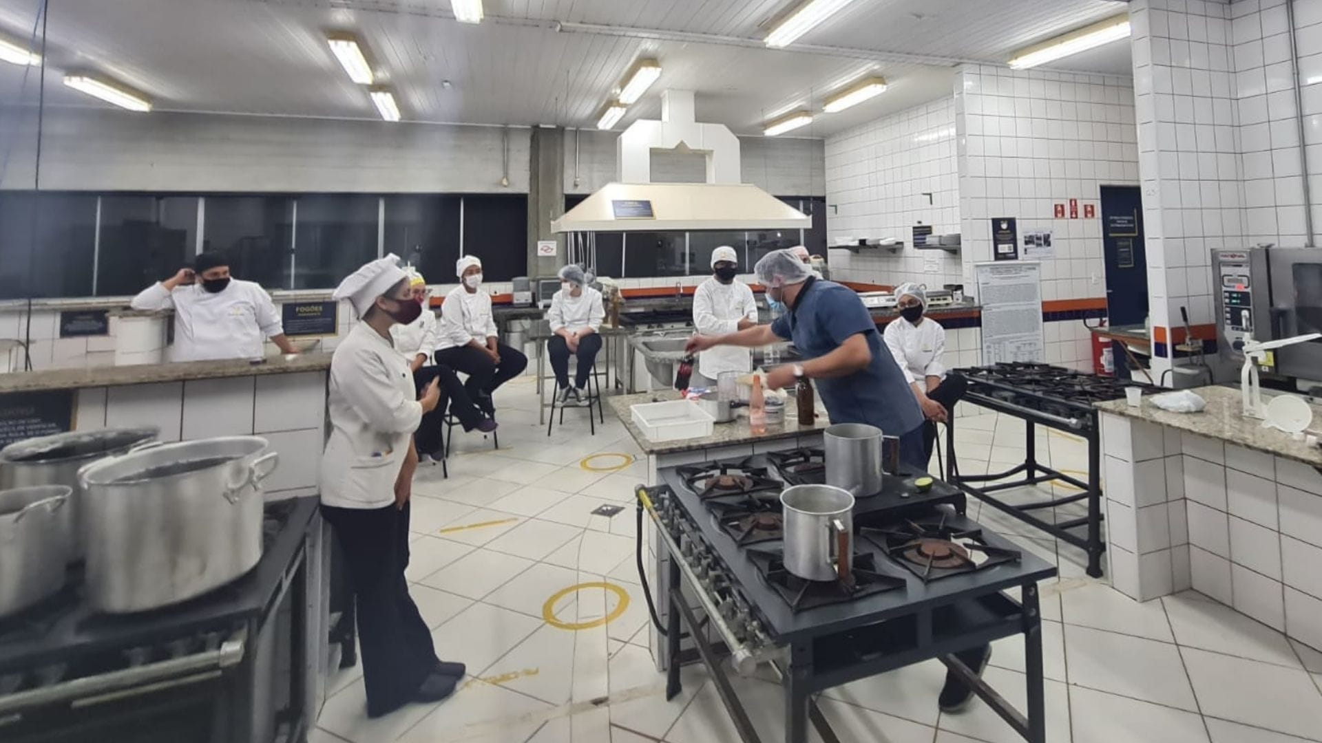 A imagem mostra o professor Tibério Gil ensinando a produção de cervejas artesanais aos alunos de Gastronomia.