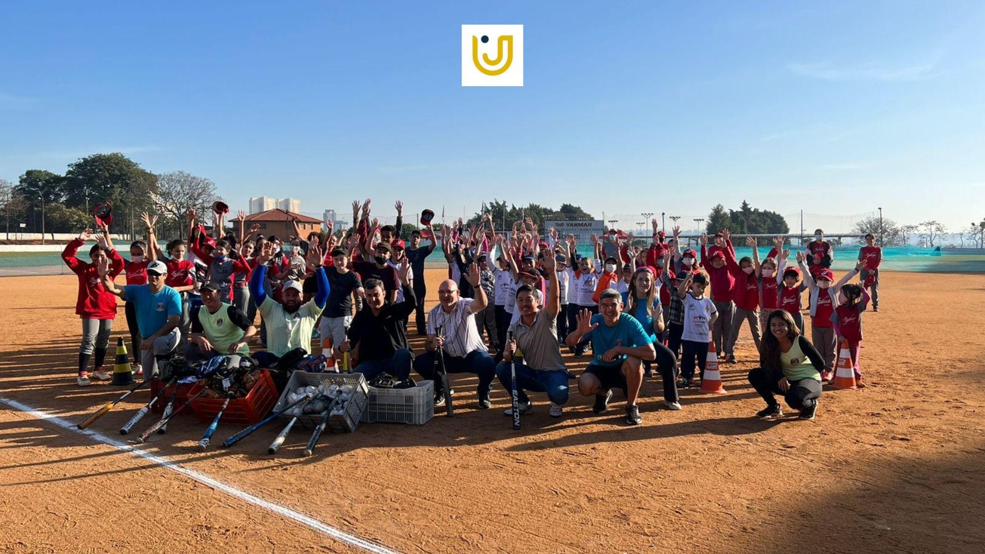 Imagem mostra crianças participantes das aulas de beisebol de Indaiatuba junto aos professores e alunos do Grupo UniEduK.